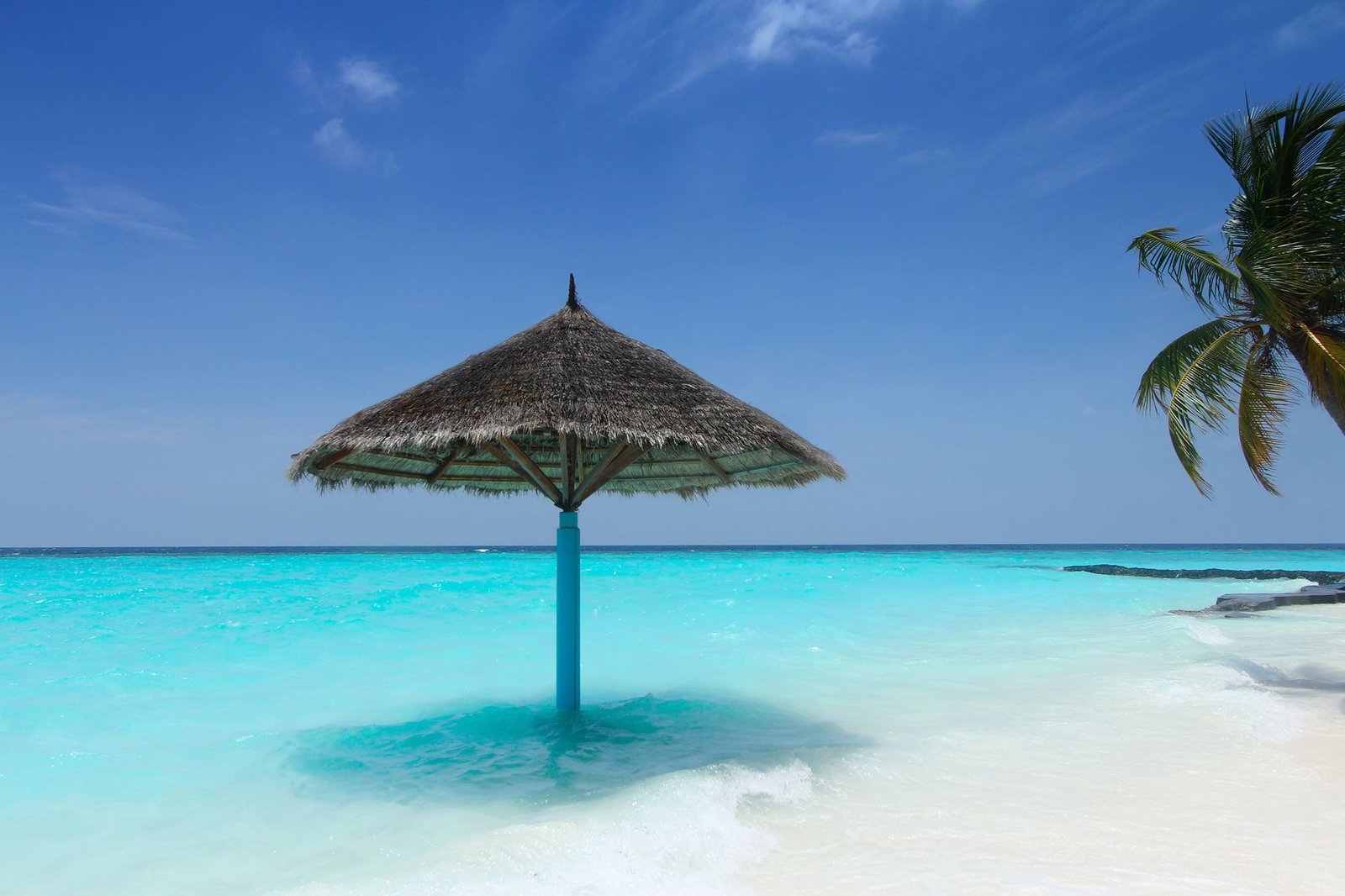 New sunscreen ingredient news: a parasol shading a tropical turquoise beach, a reminder of daily UV protection - Dr. Alaa Zidan, Maldives